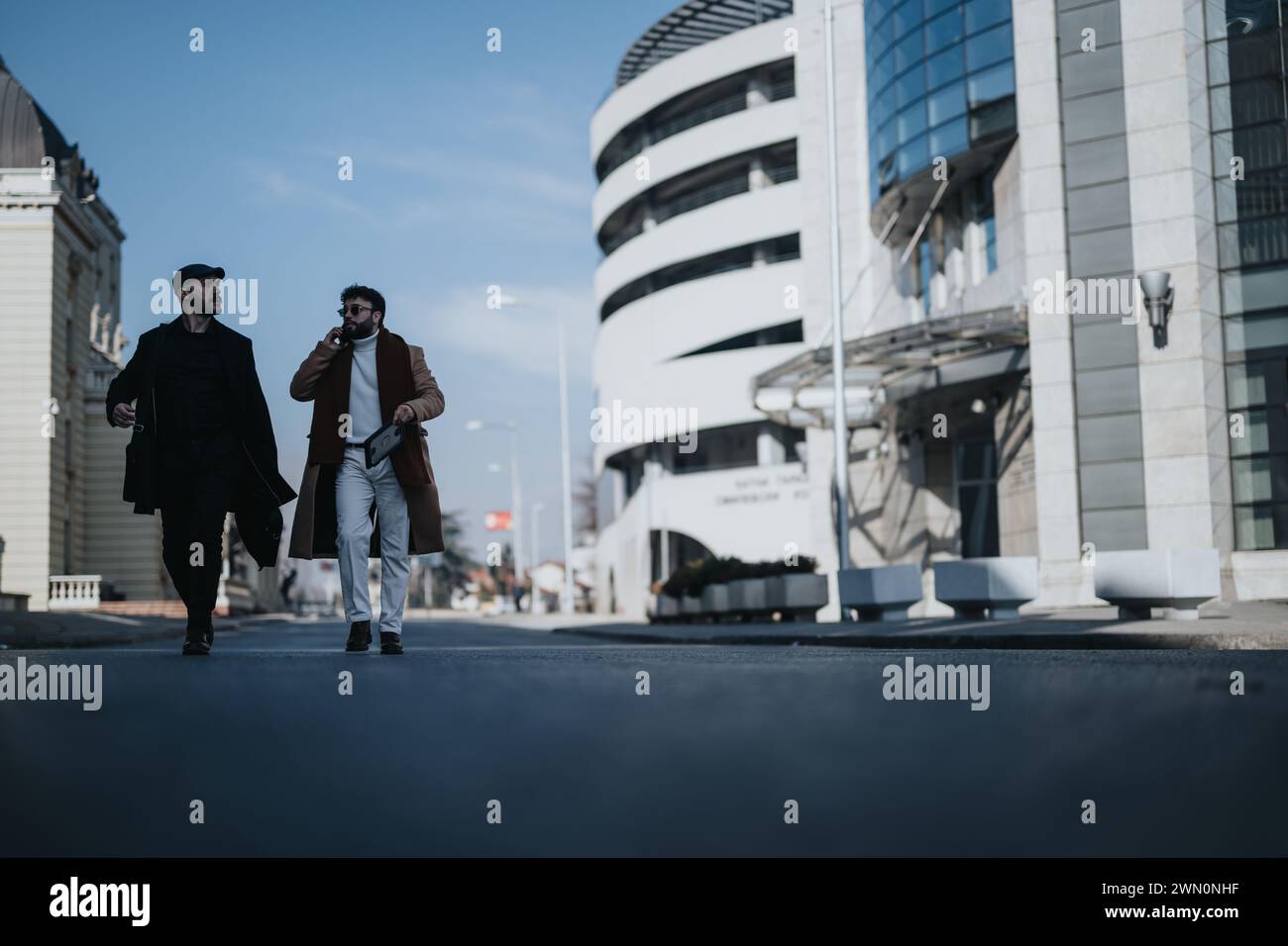 Two stylish businessmen walking and talking in a modern city ...