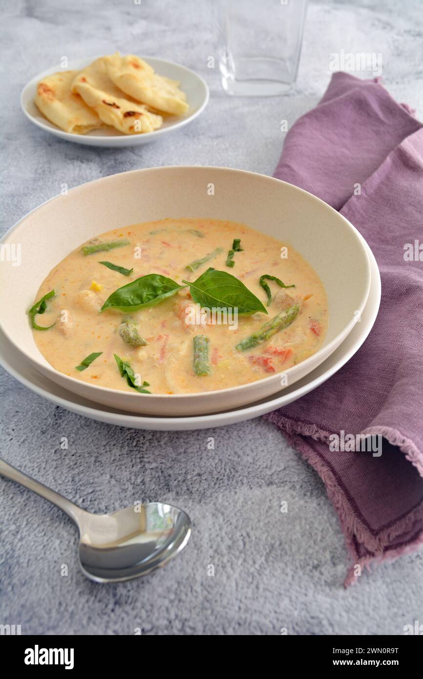 Spicy Thai coconut soup with asparagus and shrimp and naan bread in vertical format.  Tasty healthy meal. Stock Photo