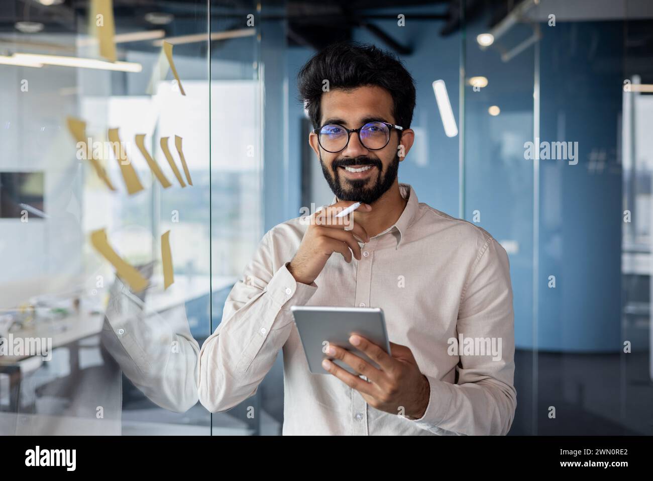 Portrait of a smiling young Indian man standing in the office near a