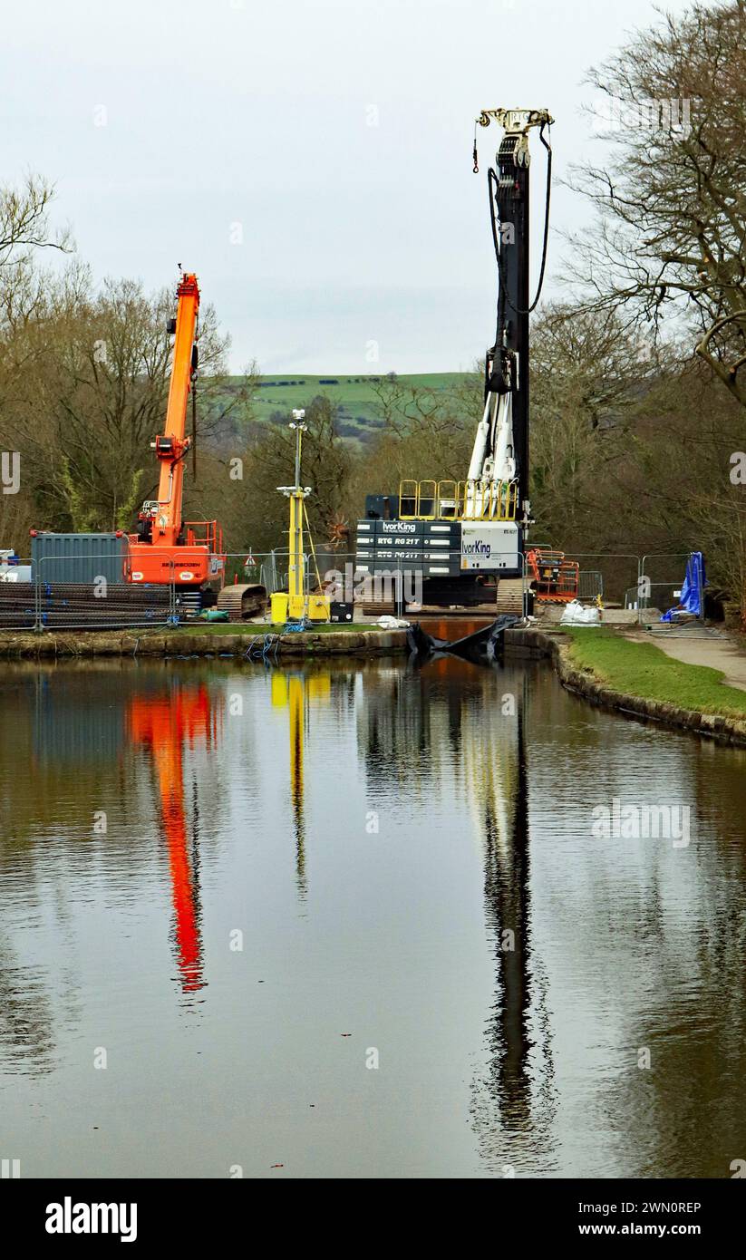 Heavy machinery reflected in the Peak Forest canal as repairs to lock 7 on the Marple flight of locks are underway on the 27th of February 2024 Stock Photo