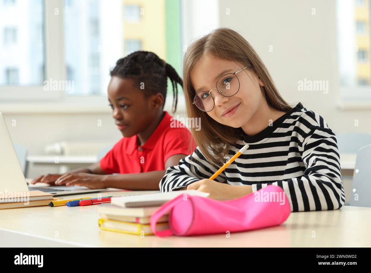 Cute girl with her classmate studying in classroom at school Stock Photo