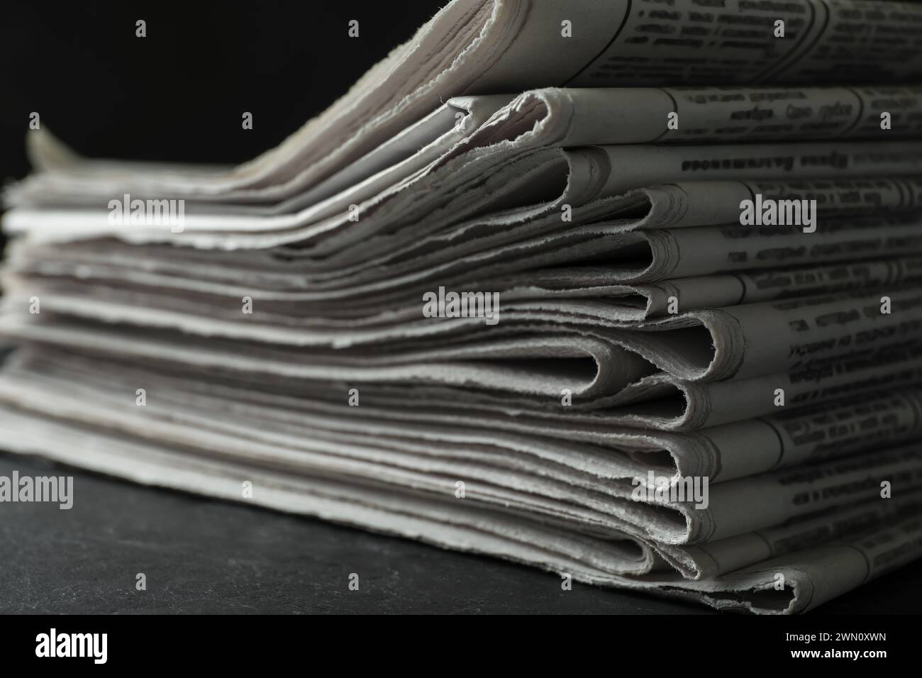 Stack of newspapers on dark stone table, closeup. Journalist's work Stock Photo