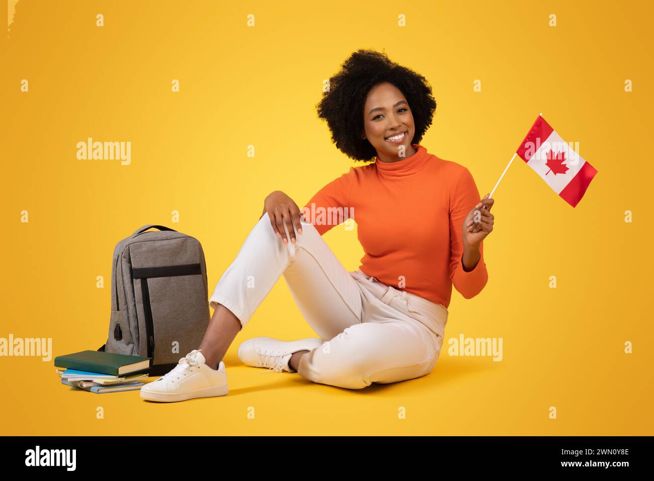 A friendly young woman with a radiant smile and curly hair sits ...