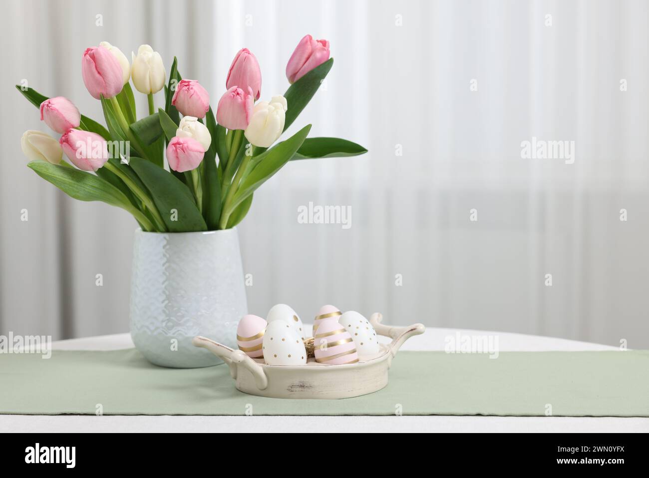 Easter decorations. Bouquet of tulips and painted eggs on white table ...