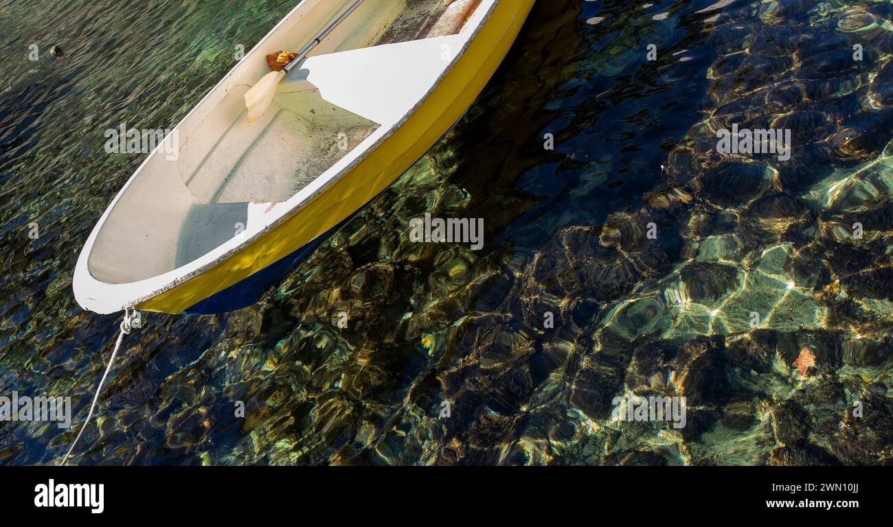 An empty yellow boat anchored in sea coast of Dubrovnik, Croatia. The water is crystal clear. Stock Photo