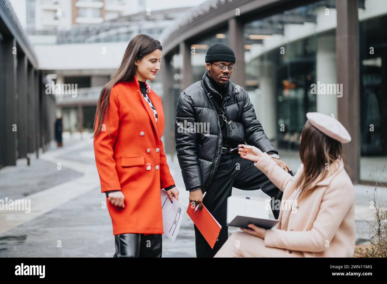 Business colleagues exchanging documents outdoors in urban setting Stock Photo