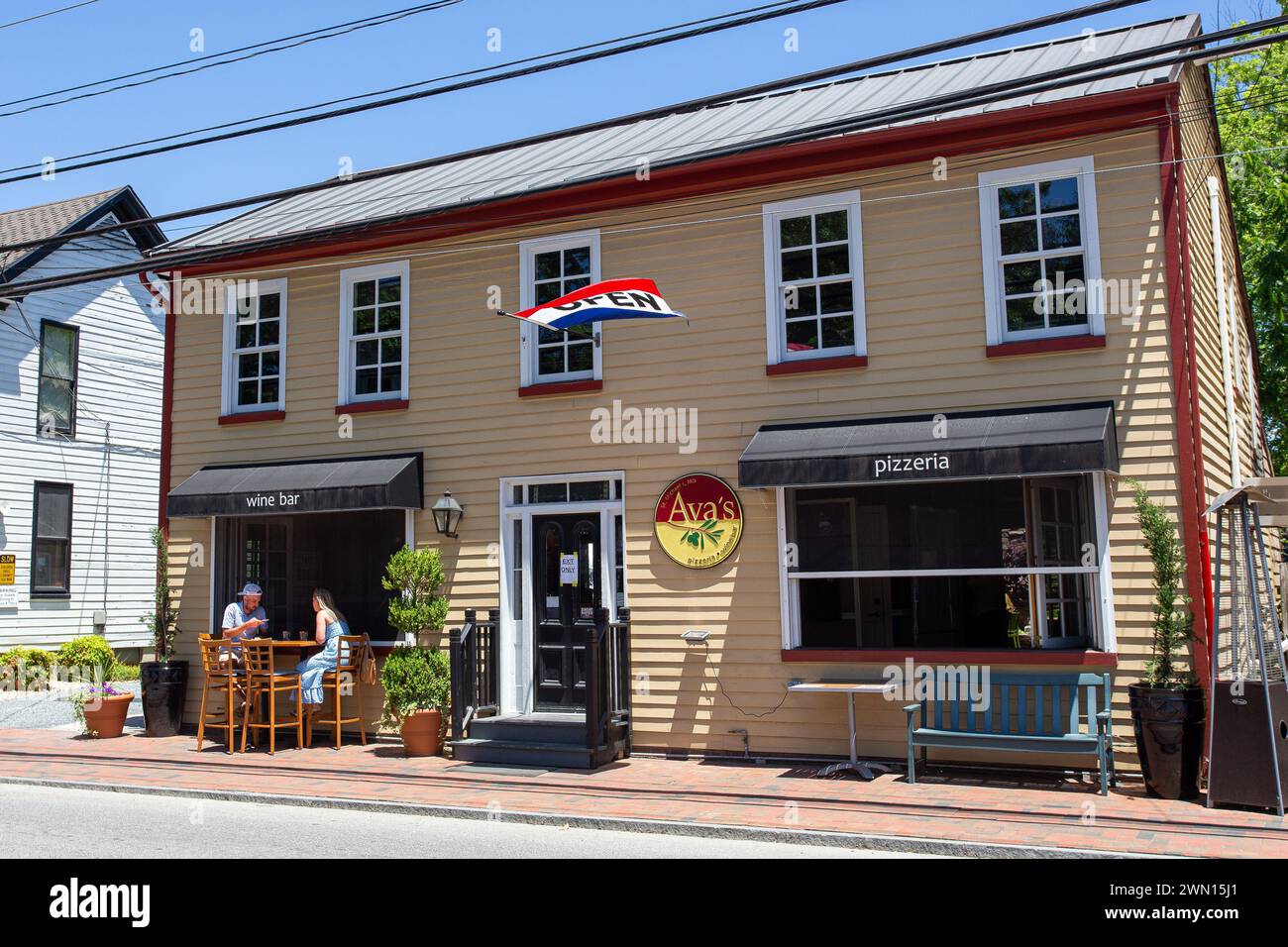 A delightful daytime street scene at Avas Pizzeria showcasing outdoor dining and American flag in a quaint town setup Stock Photo