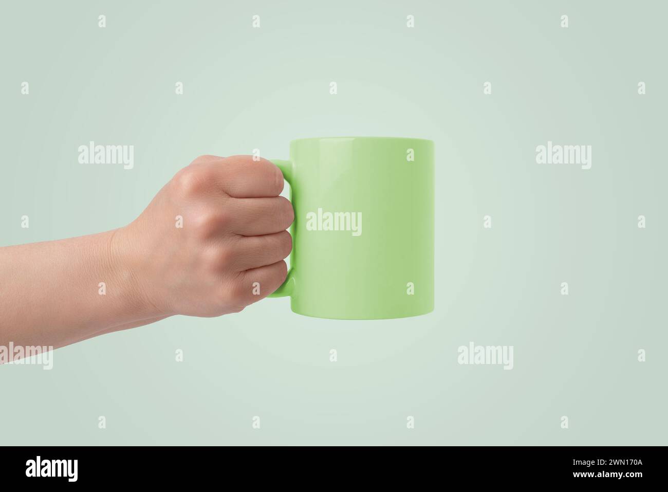 Green cup held in hand with empty surface for branding mockup Stock Photo