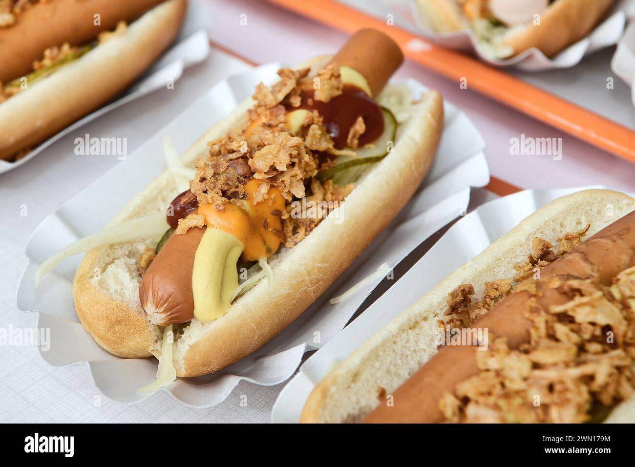 Frankfurter sausage hot dogs served with crispy onion bits and relish, on paper plates Stock Photo