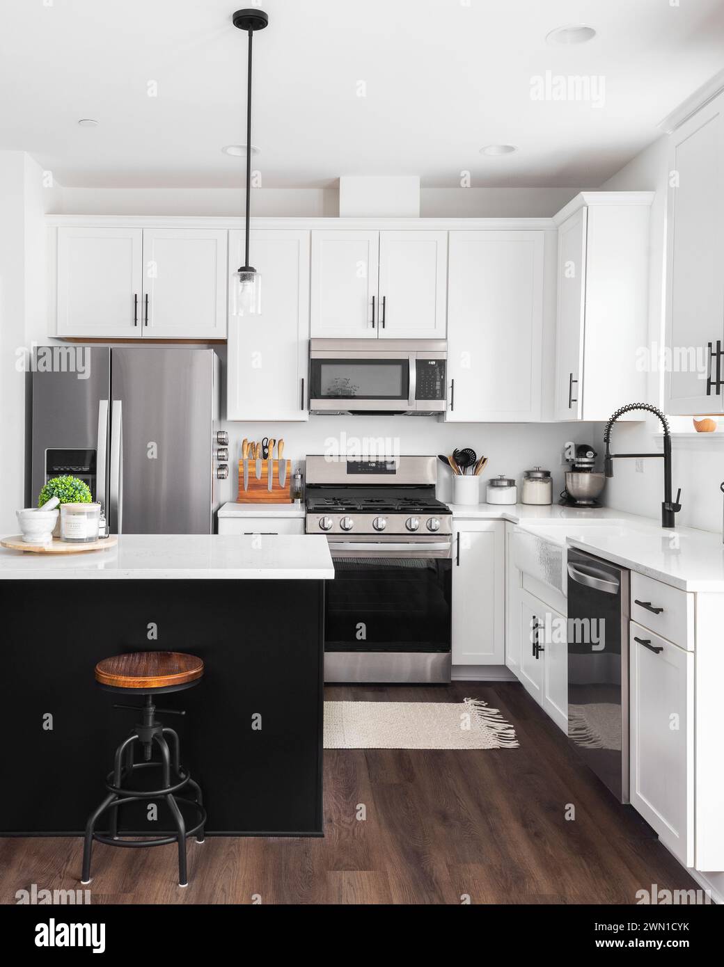 A modern farmhouse kitchen with white cabinets and a black island