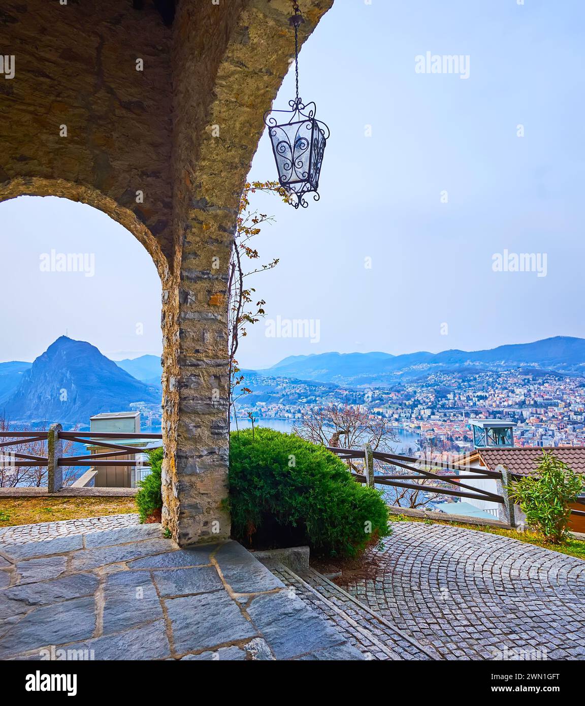 The old stone portico of Aldesago Church opens the view on Ceresio and scenic Monte San Salvatore, Lugano, Switzerland Stock Photo
