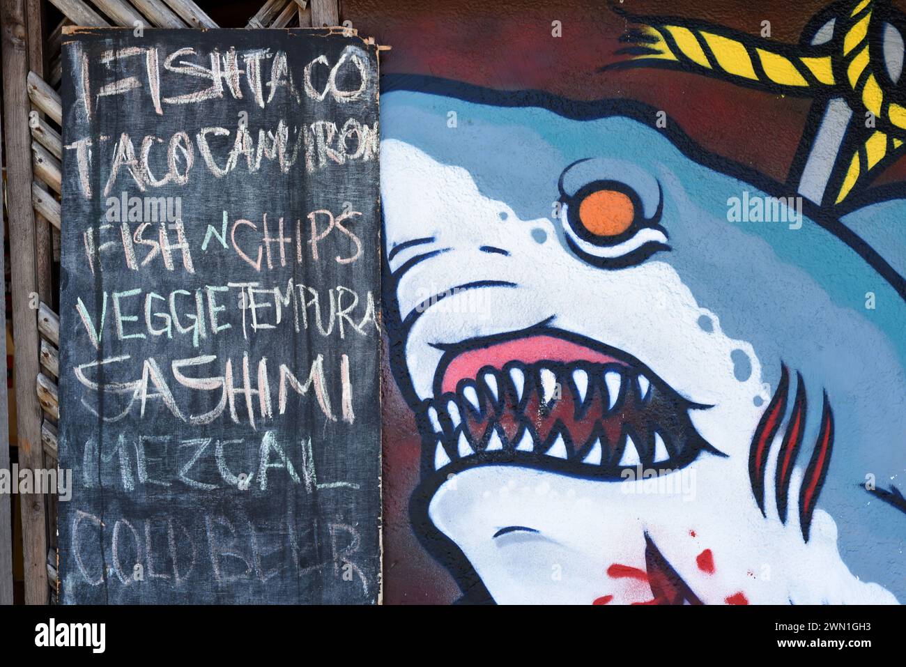 A chalkboard menu for a restuarant next to a shark painting in the Playa Zicatela neighbourhood in Puerto Escondido, Oaxaca, Mexico Stock Photo
