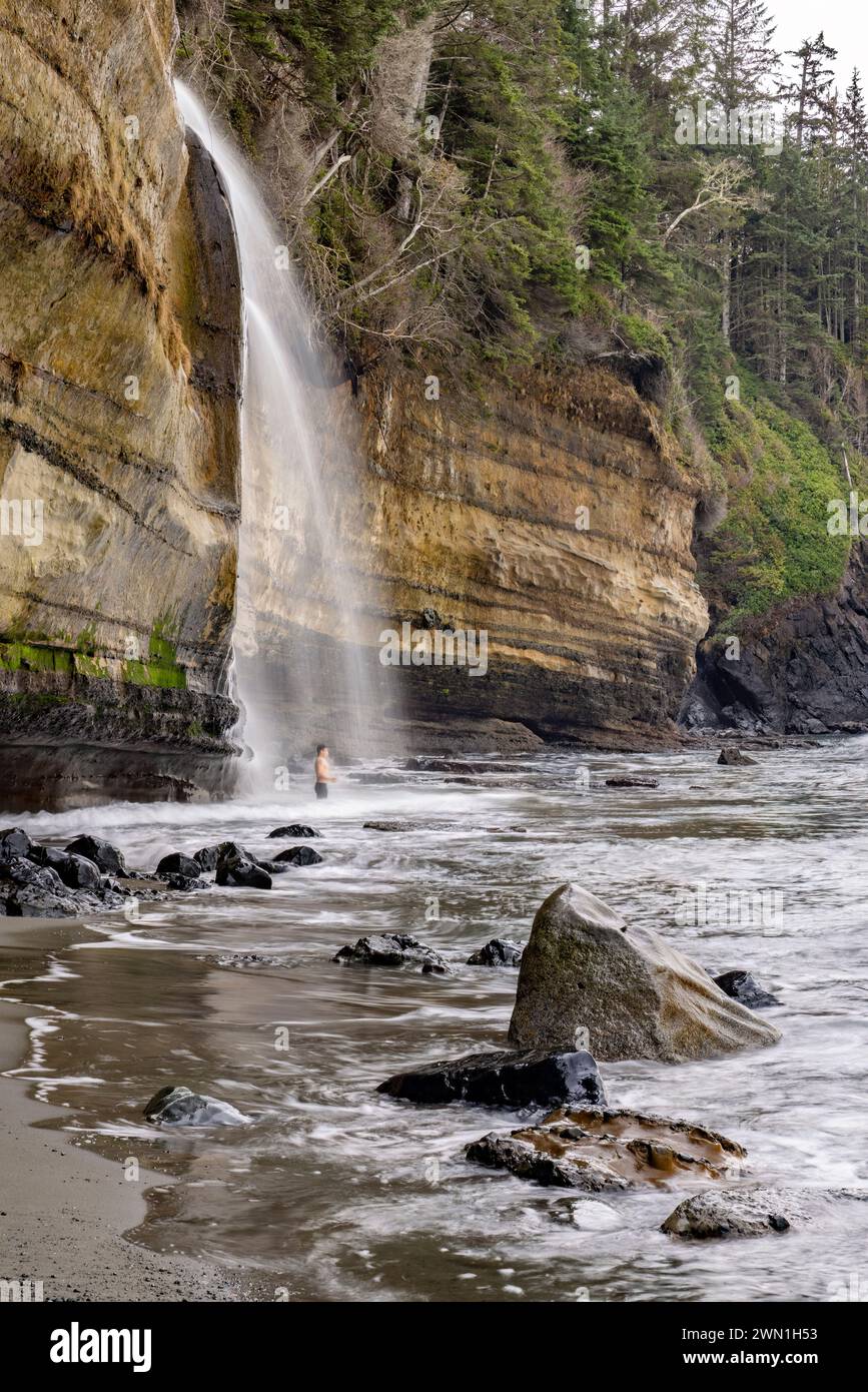 Person standing in the cold waters of Mystic Beach Falls - near Sooke, Vancouver Island, British Columbia, Canada Stock Photo
