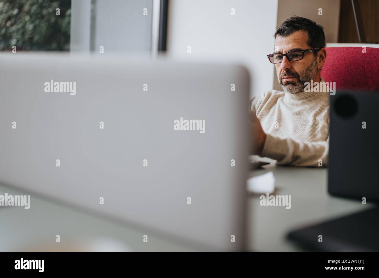 Focused professional man working at a computer desk in modern office Stock Photo