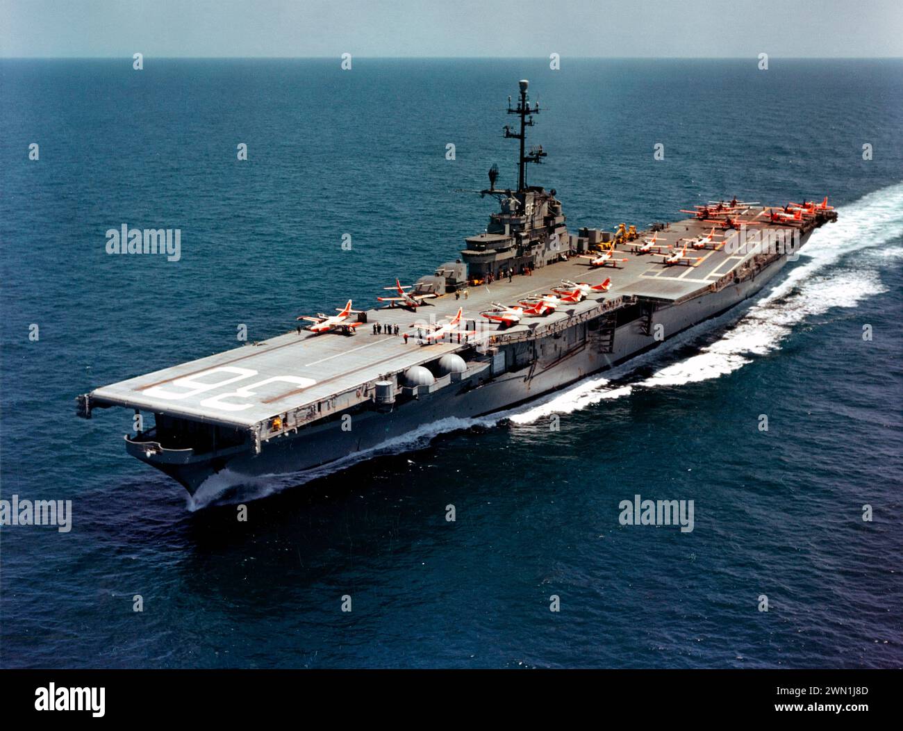 The U.S. Navy aircraft carrier USS Antietam (CVS-36) Operating training aircraft, 19 April 1961. Planes on deck include North American T2J-1 Buckeyes amidships and forward and Douglas AD Skyraiders parked aft. Note the dayglo paint on the aircraft and the mothballed 127 mm/38 guns in the carriers port side sponsons 1961 Stock Photo