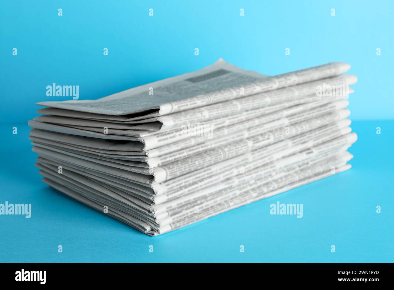 Stack of newspapers on light blue background. Journalist's work Stock Photo