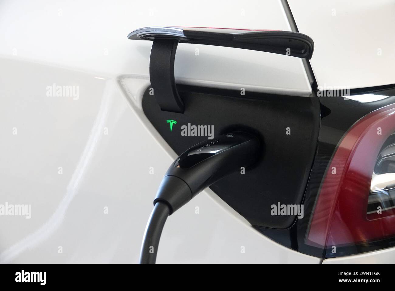 Tesla EV charging in a home garage plugged into a wall charger Stock Photo
