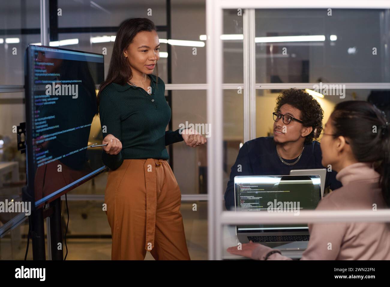 Ethnically diverse programmers working together on code at workplace in IT company office late in evening Stock Photo