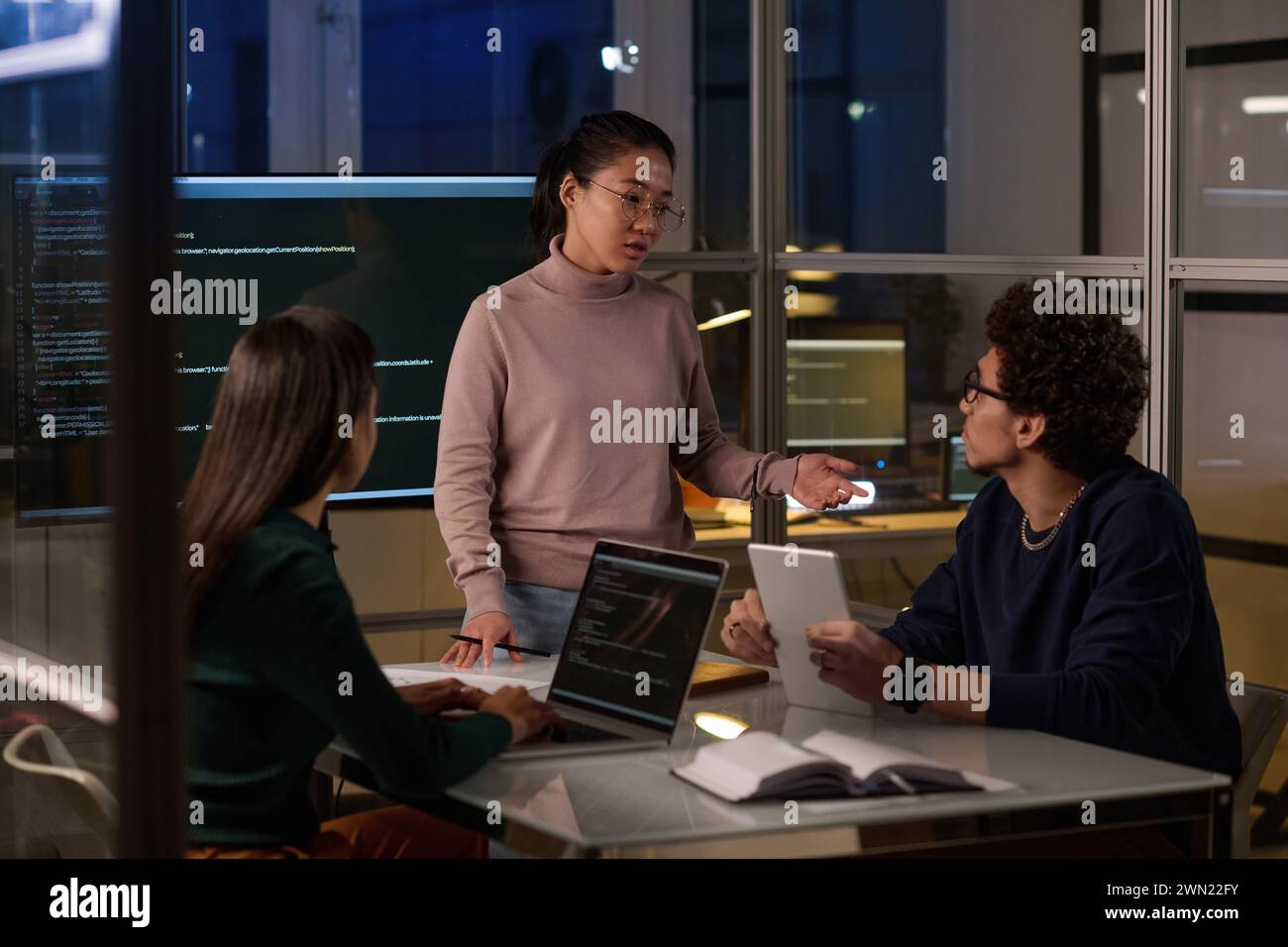 Group of ethnically diverse programmers spending evening in office working together on computer code Stock Photo