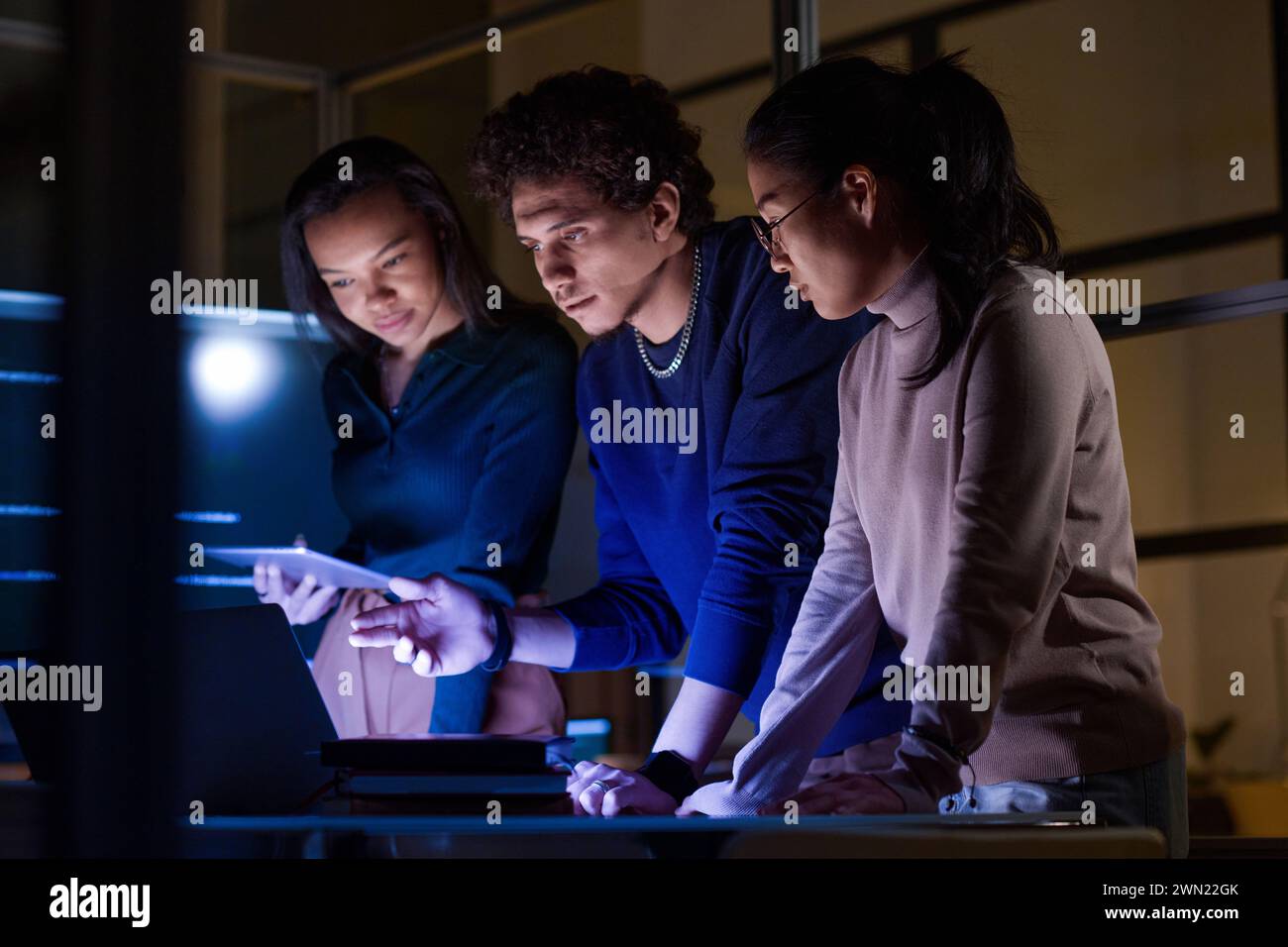 Group of modern young IT specialists developing and testing new software late in evening Stock Photo