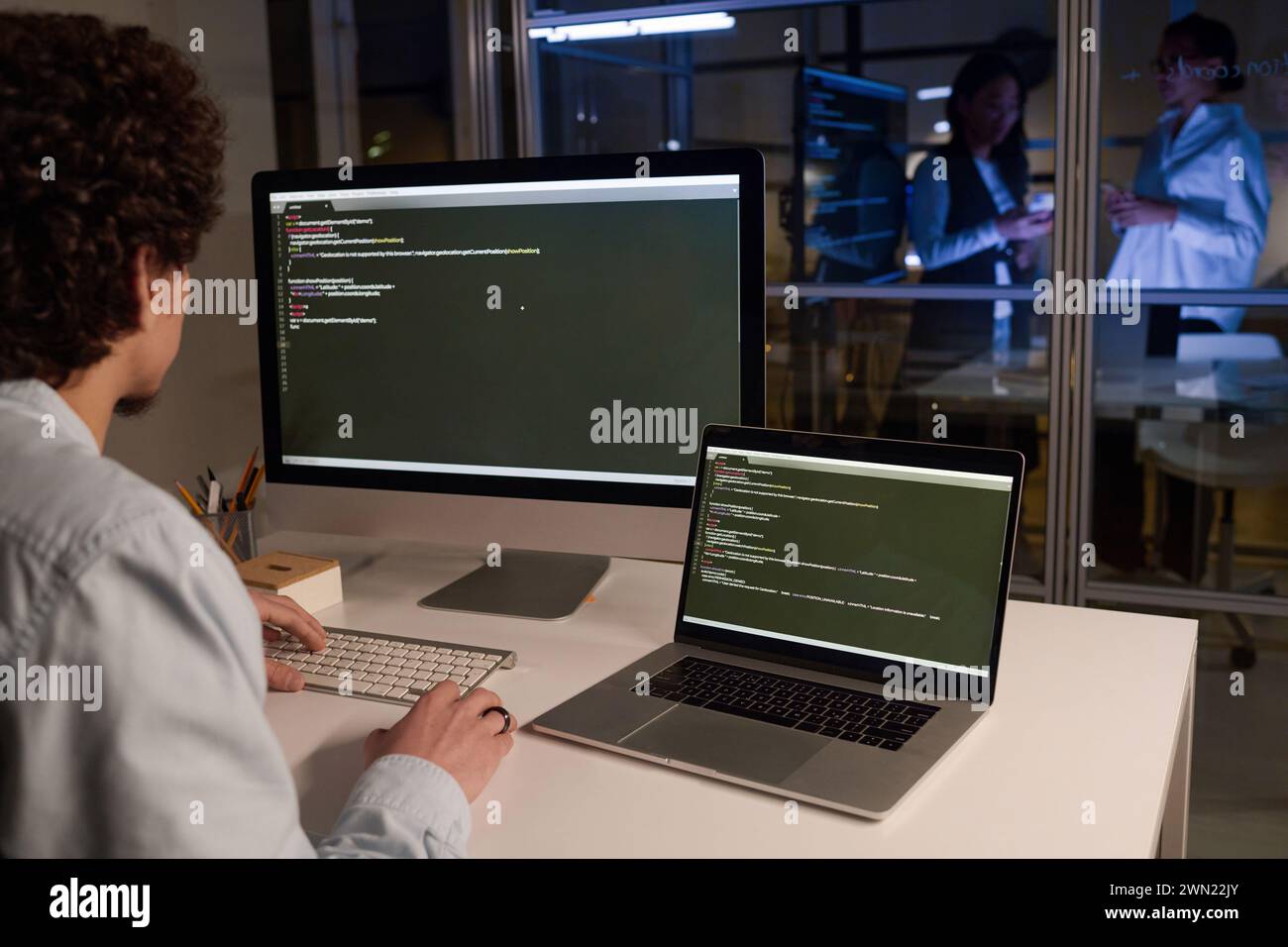 Unrecognizable male programmer developing code typing on computer late in evening, copy space Stock Photo