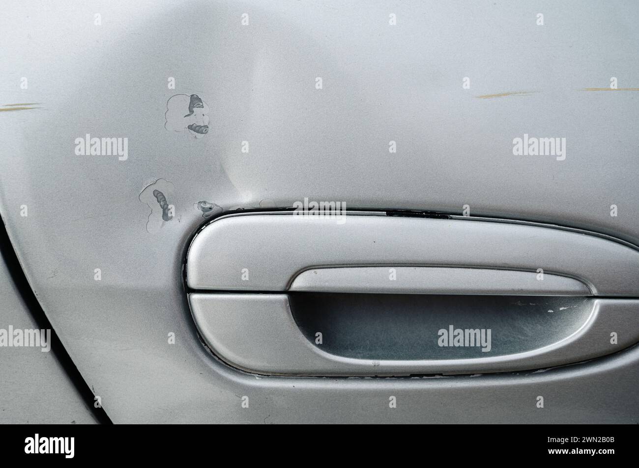 car after an accident with a damaged dented and scratched door on the side close-up Stock Photo