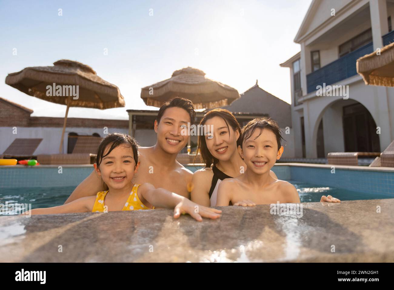 Happy young family having fun in swimming pool Stock Photo