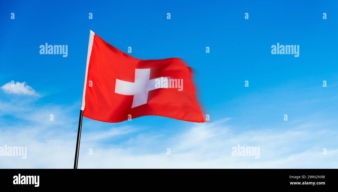 Swiss flag waving against blue sky Stock Photo