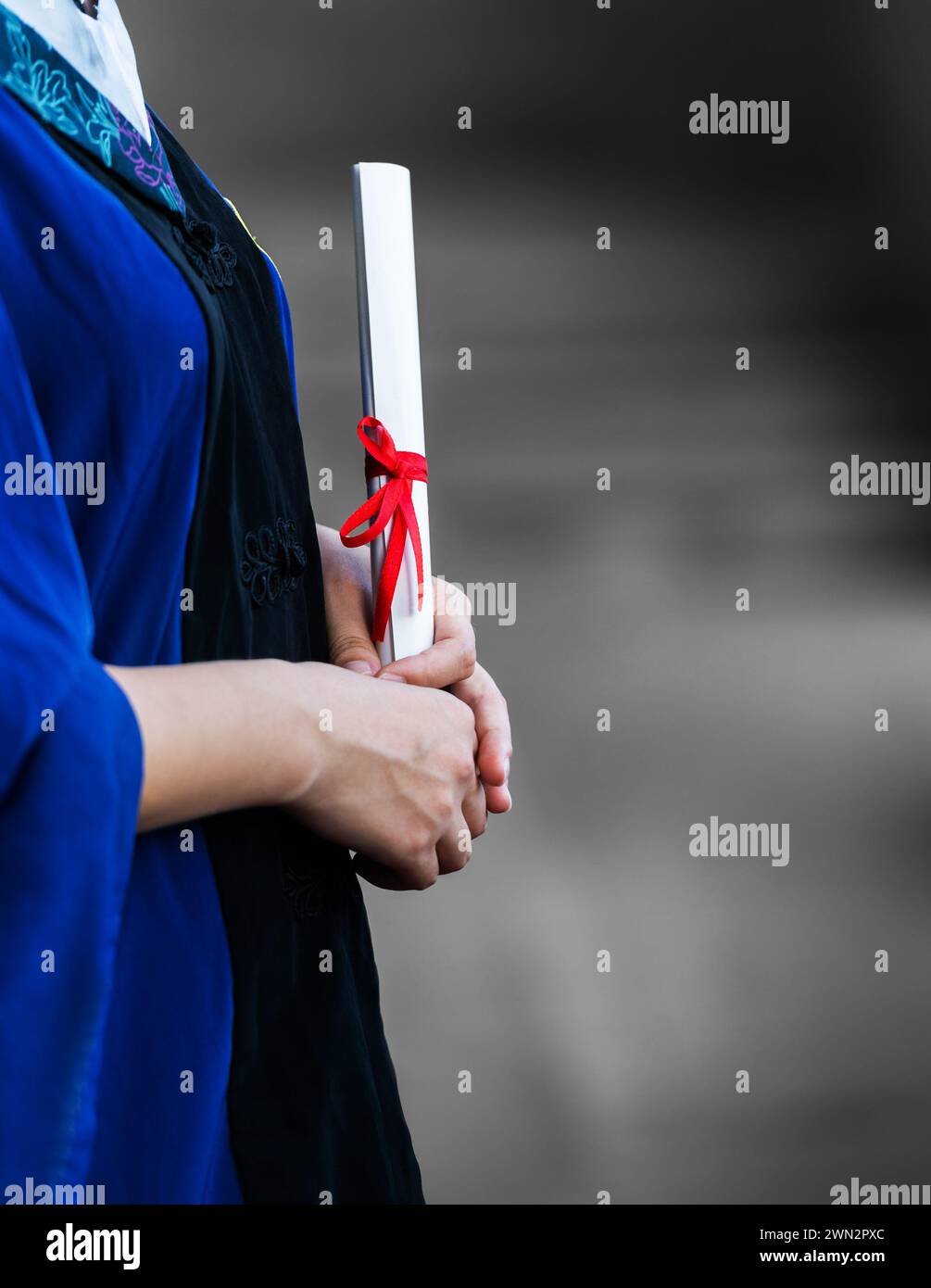 Detail of female student in gown holding a diploma Stock Photo