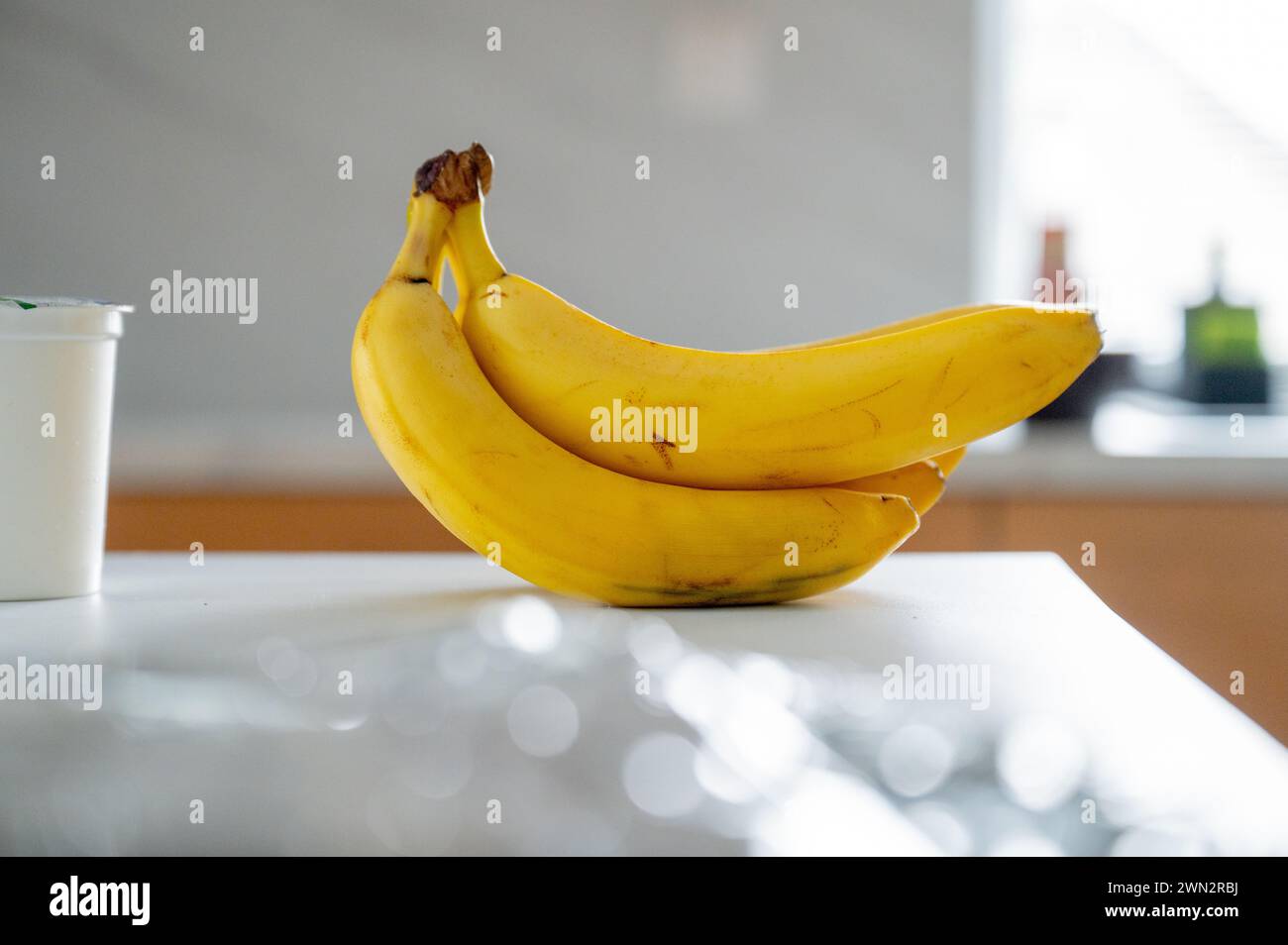 Soft daylight frames a lone banana on the kitchen island Stock Photo