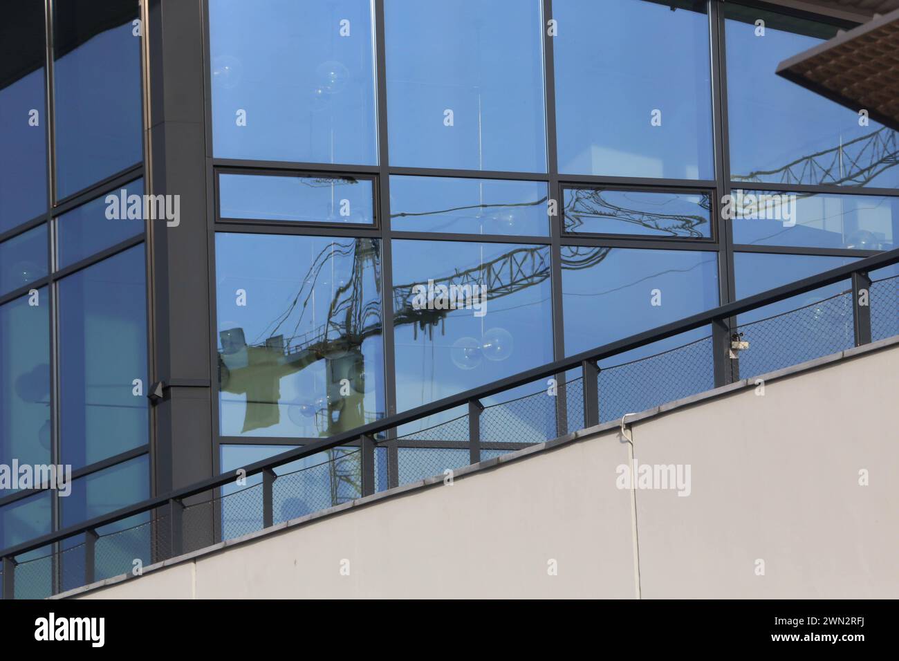 Ein Baukran spiegelt sich am Montag 26.02.2024 in der Hanse- und Universitätsstadt Rostock in einem Fenster der örtlichen Stadthalle. Die Ampel-Koalition hatte einst das Ziel herausgegeben, 400.000 neue Wohnungen zu schaffen. Ob das jemals erreicht wird ist derzeit mehr als fraglich. Denn zahlreiche Bauherren sind in den zurückliegenden Monaten wegen der gestiegenen Kosten von einem Teil ihrer ursprünglichen Bauvorhaben zurückgetreten. Hinzu kommen Lieferengpässe bei Baumaterial. Außerdem leidet die Bauwirtschaft nach wie vor unter einem massiven Fachkräftemangel. Und momentan ist kein Ende ab Stock Photo