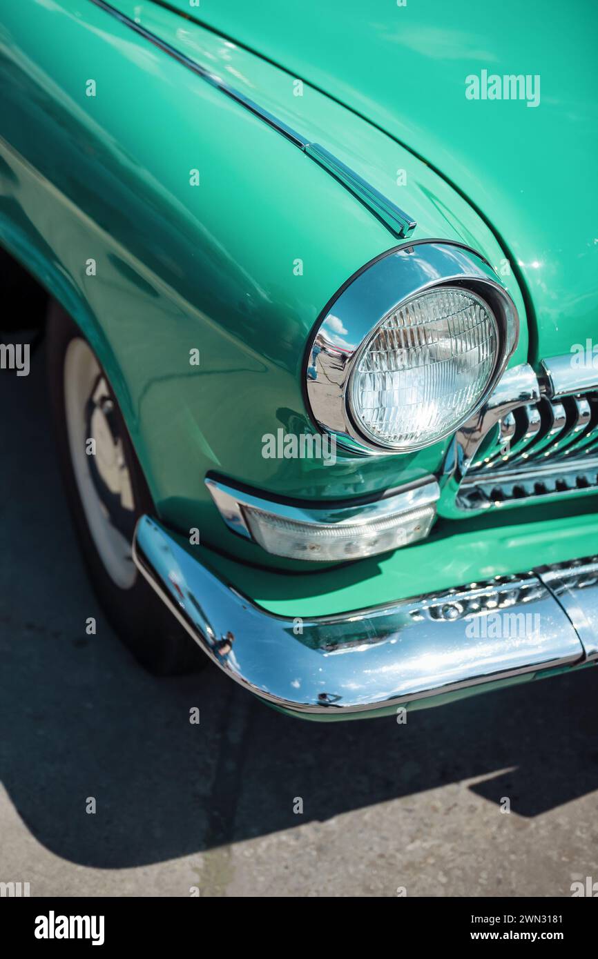 Front right corner view of old turquoise 1950s car - headlight, grill, fender, bumper hood and wheel. Classic car with round shapes and lots of chrome Stock Photo