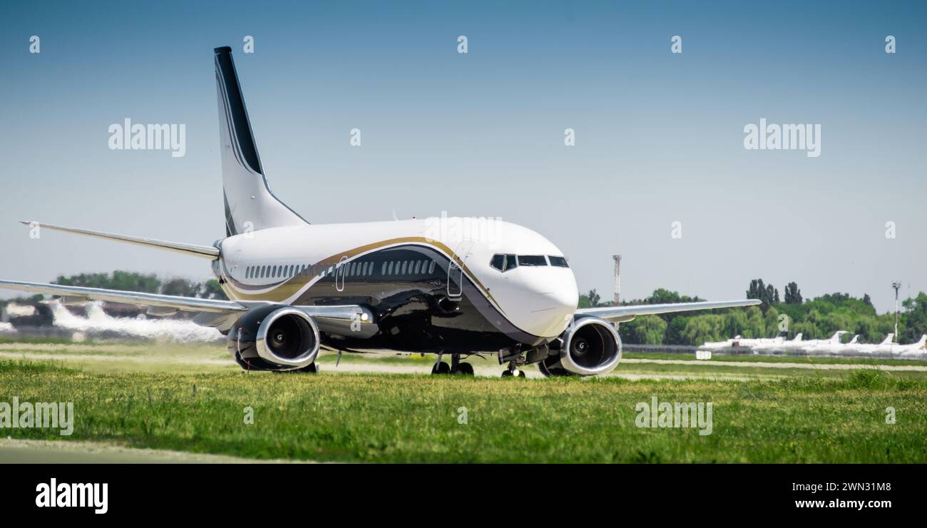 White passenger aircraft moving on airport taxiway. Hot air coming out of the back of the engine and distorts the visibility. Stock Photo