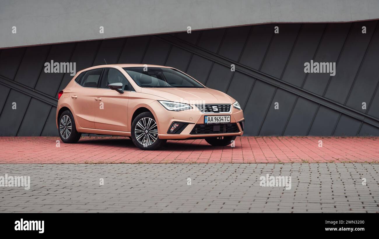 beige SEAT Ibiza in front of modern building. Front three quarter view of compact pale ivory spanish hatchback parked in urban setting. Stock Photo