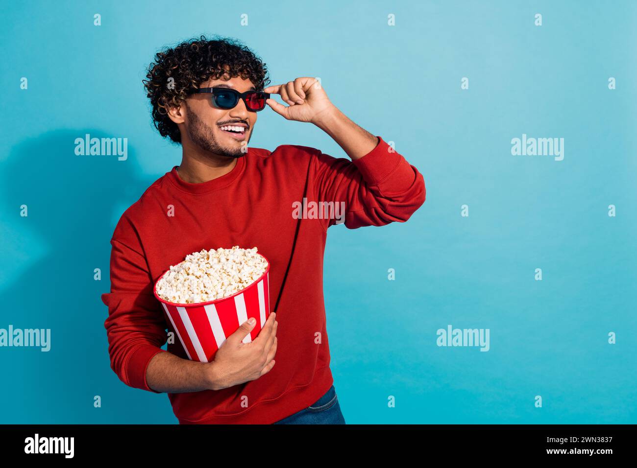 Photo of young funny indian student holding popcorn bucket when watch