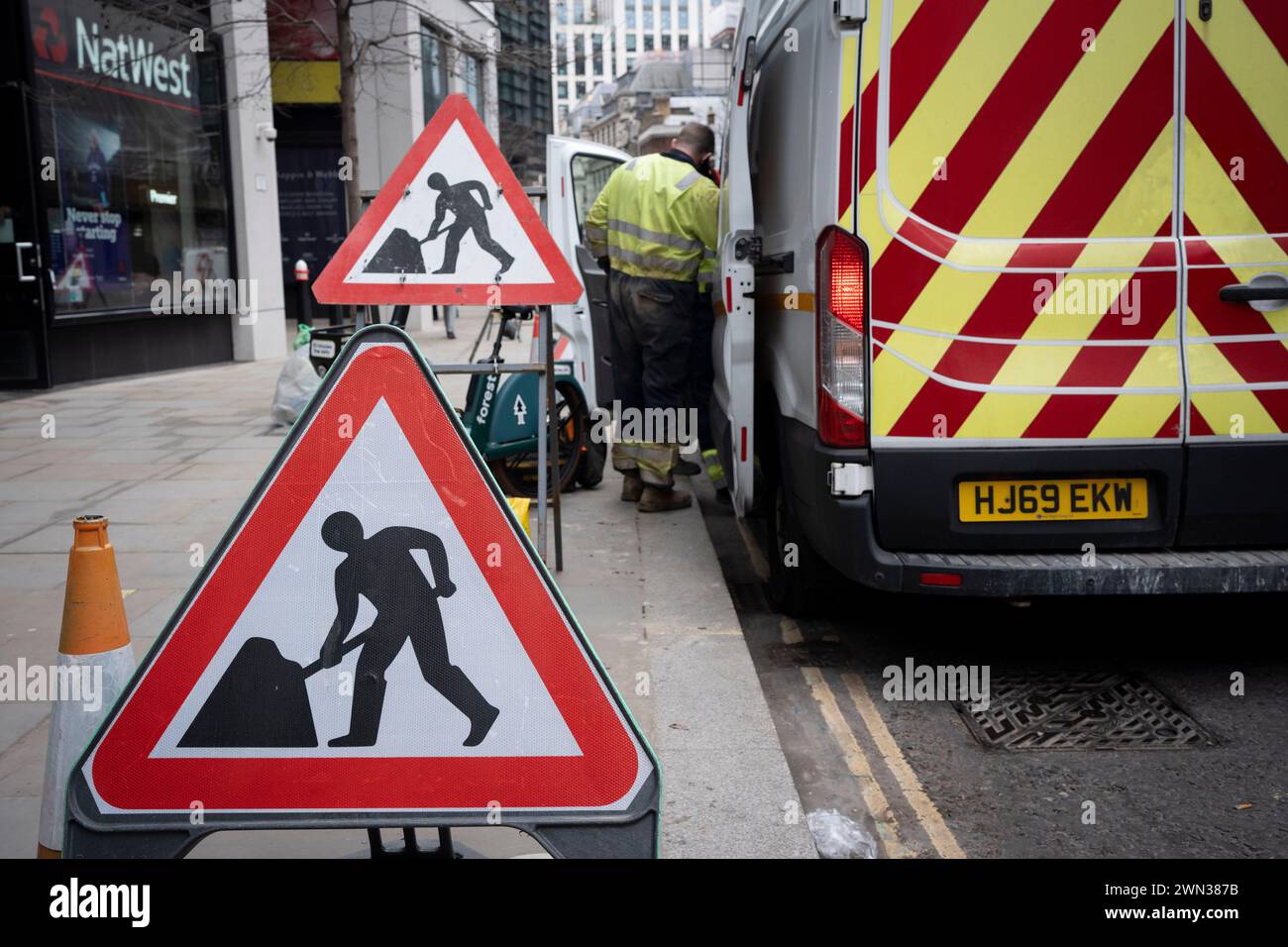 Man at work warning signs during street works by contractors in the City of London, the capital's financial district, on 28th February 2024, in London, England. Stock Photo