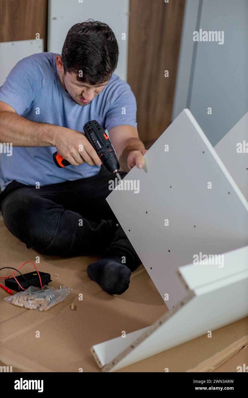 Man assembling furniture by using cordless screwdriver. Stock Photo