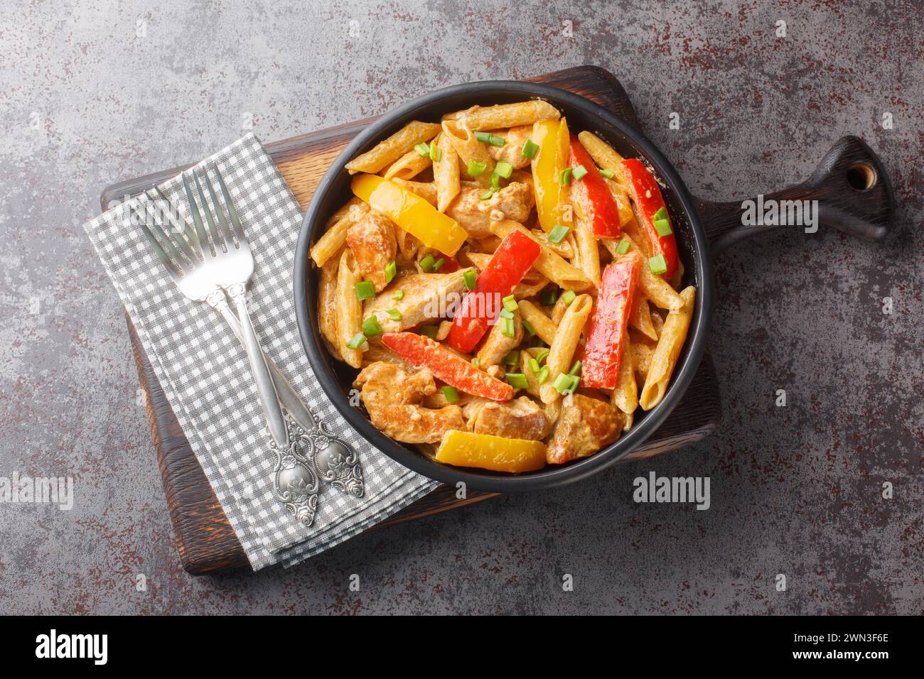 Jamaican Style Rasta Pasta Penne with Grilled Chicken and Bell Peppers closeup on the bowl on the wooden board. Horizontal top view from above Stock Photo