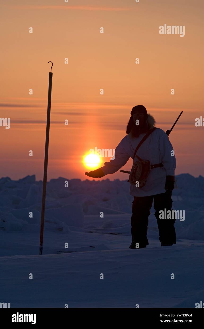 Inupiaq hunter seal hunting near open lead holding sun at sunset at the point of Point Hope Tigia Arctic Alaska Stock Photo