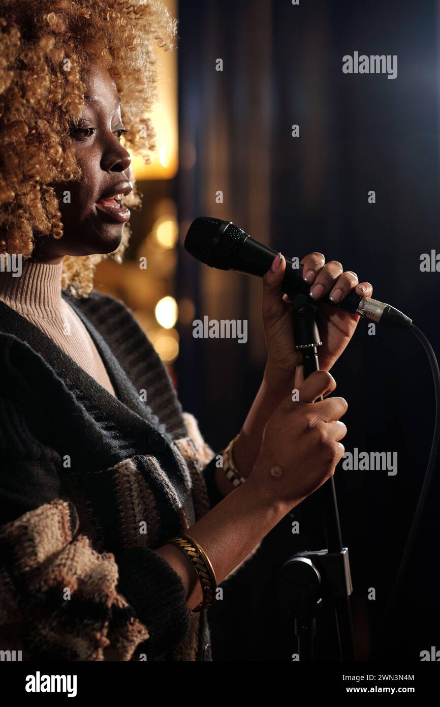 African American female comedian with microphone standing on stage in front of audience while