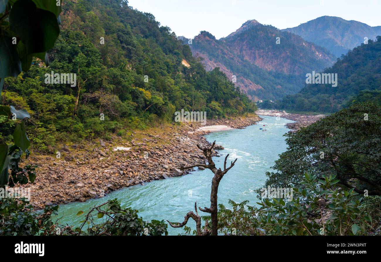 Ganges Majesty: Flowing Sacred River amidst Green Waters & Uttarakhand's Mountainous Splendor in Rishikesh, India Stock Photo