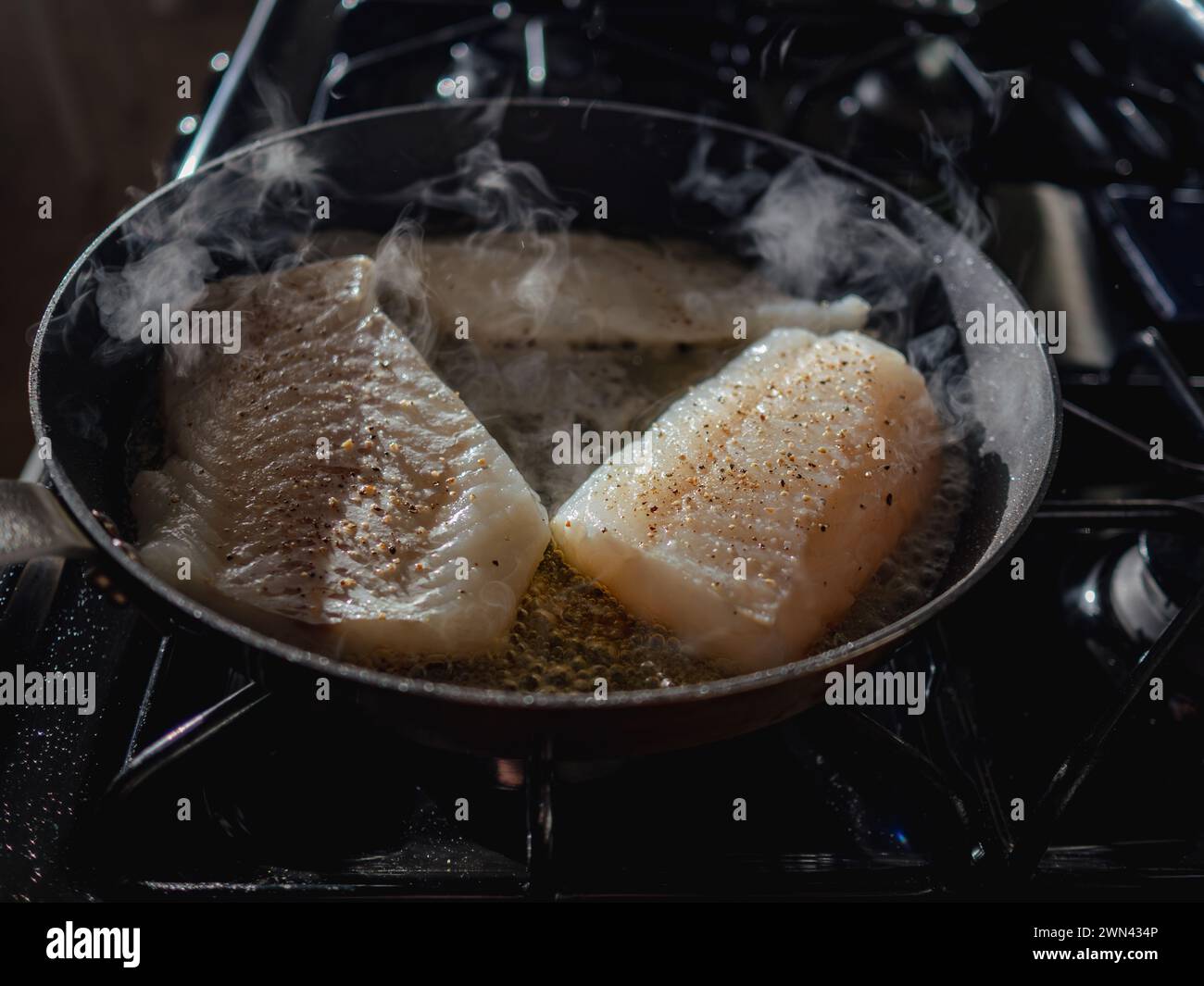 The cod in skillet being cooked in the hot pan Stock Photo - Alamy
