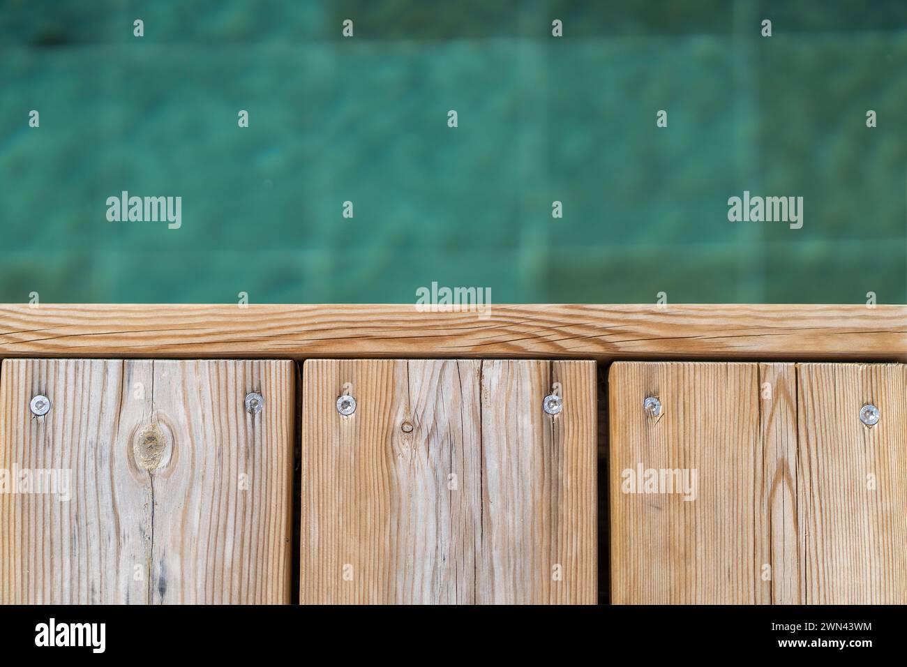 Poolside wooden deck and turquoise blue water of pool, view from the top Stock Photo