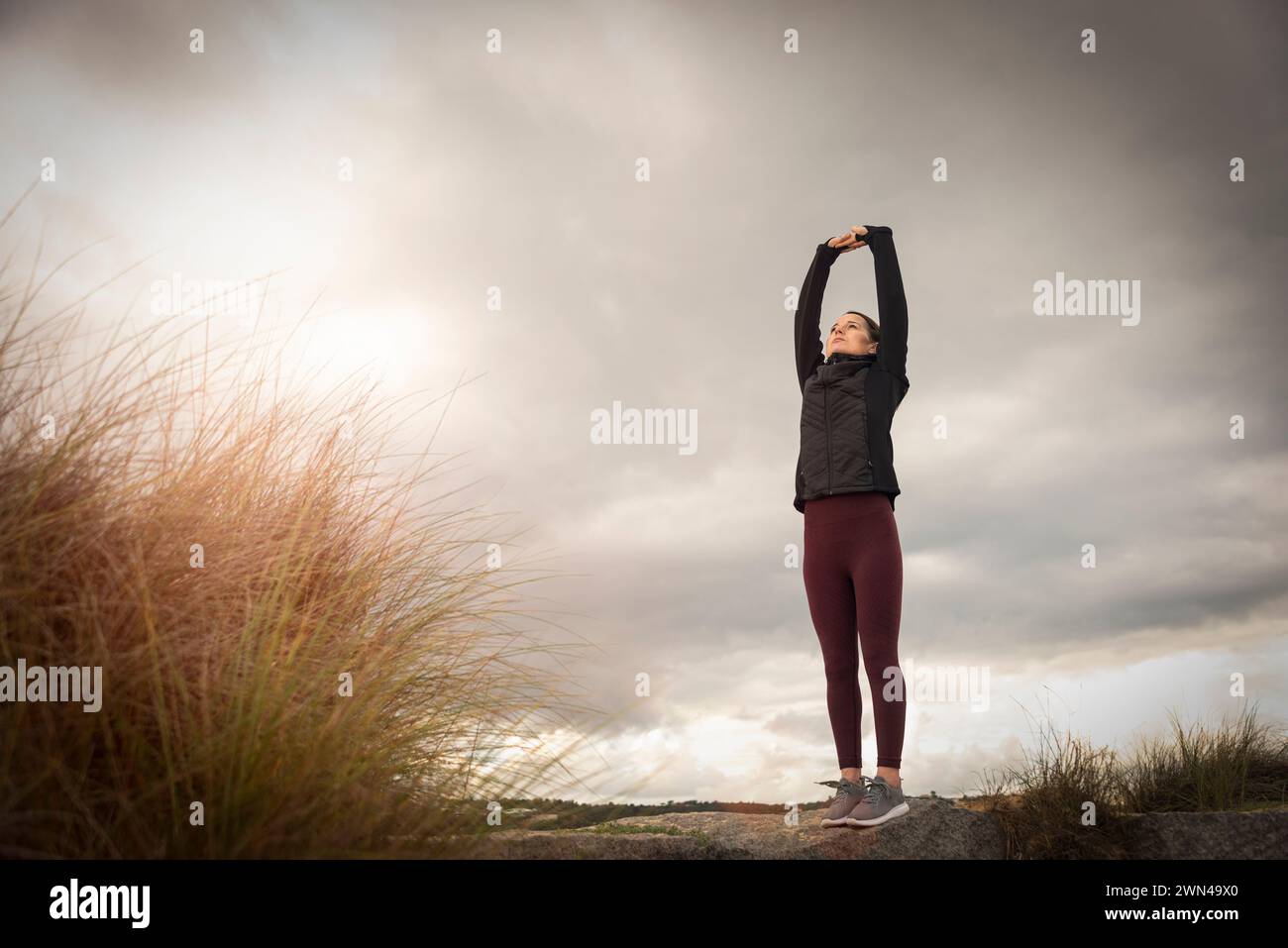 Woman doing stretching exercises outside at sunrise. Stock Photo