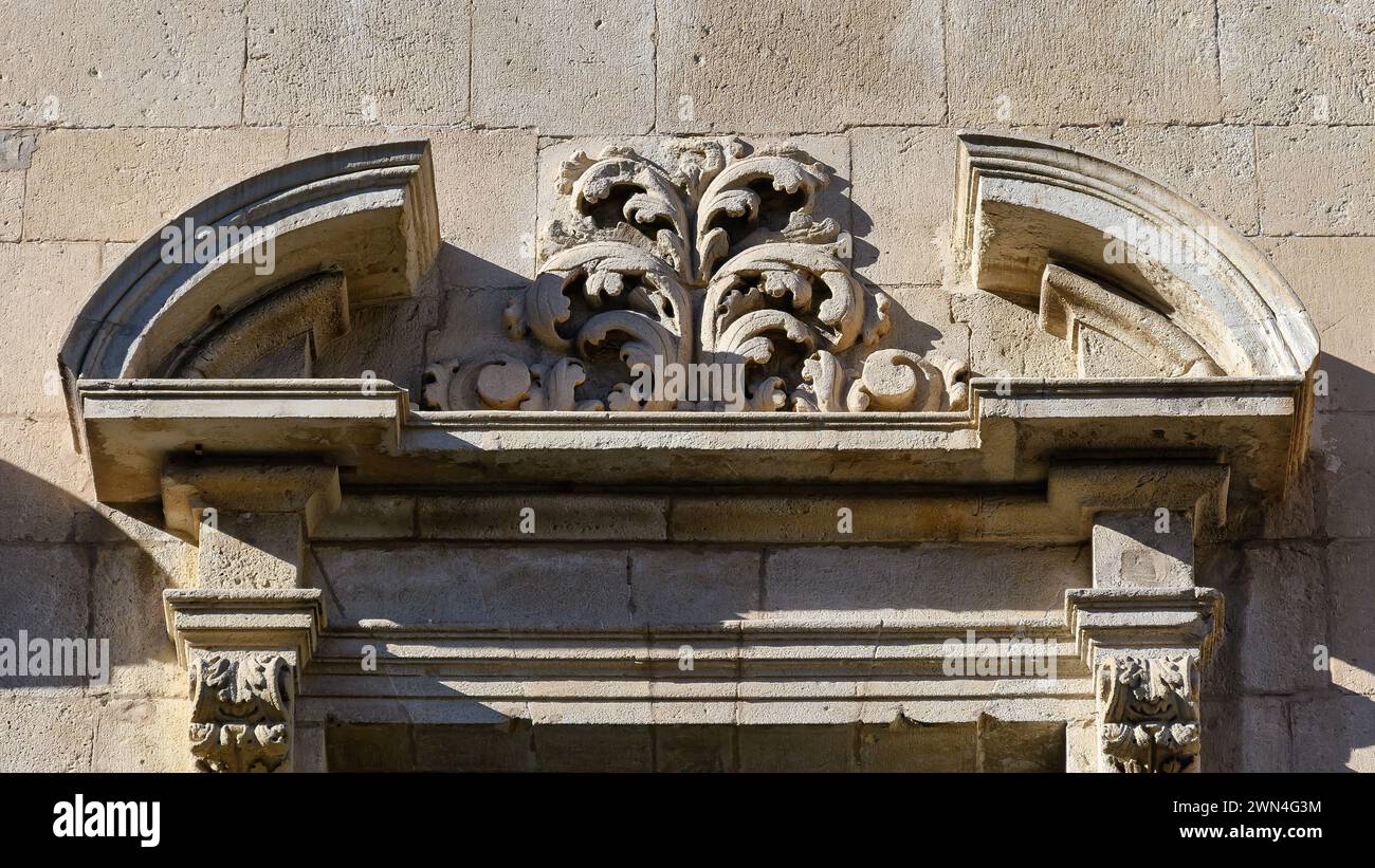 Architectural capital decoration on top of a window in a medieval stone building, Alicante, Spain Stock Photo
