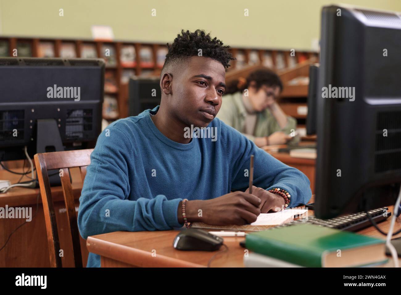 Portrait of young African American man as male student using computer ...