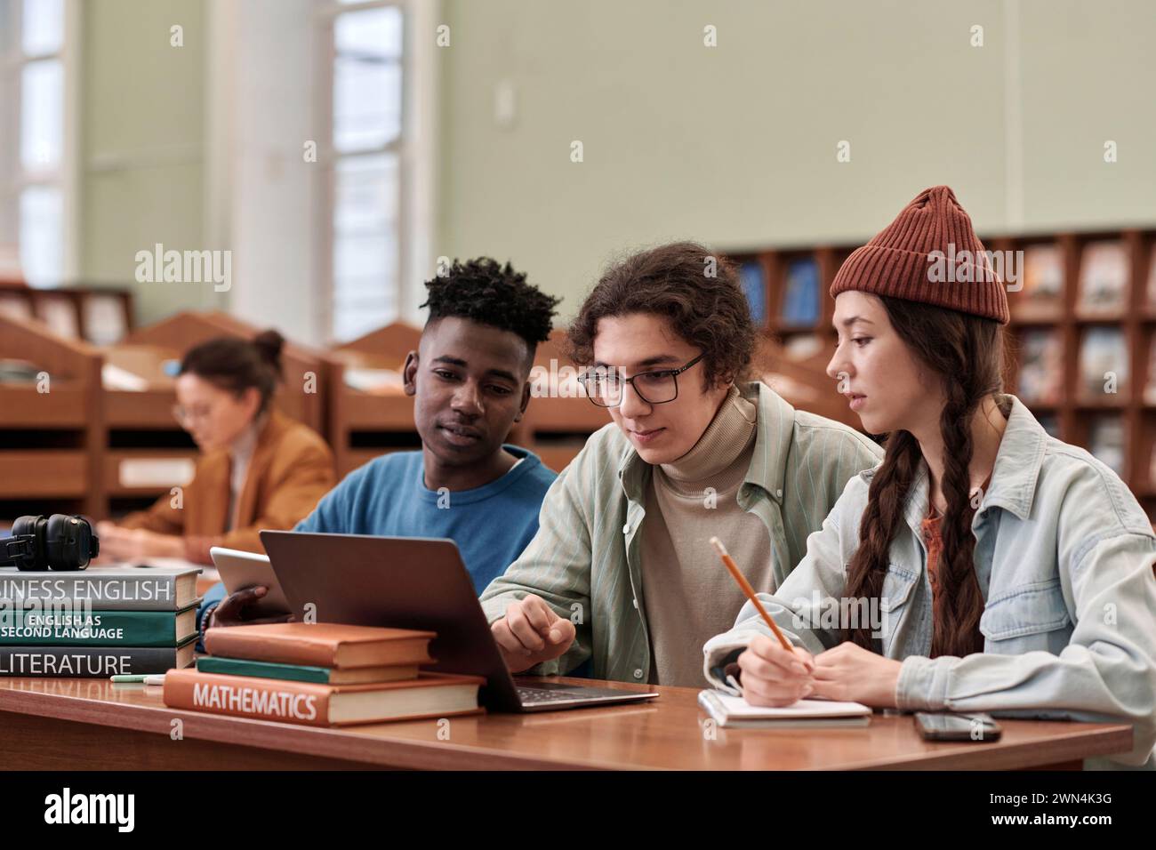 Multiethnic group of three young students using laptop together in ...