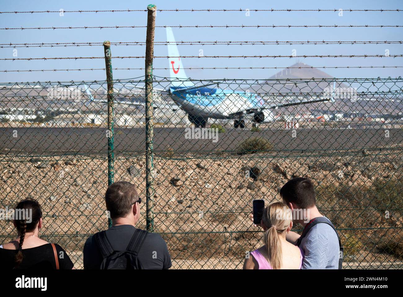 tourists watching planes take off from the airport perimeter footpath at the end of the runway Lanzarote, Canary Islands, spain Stock Photo