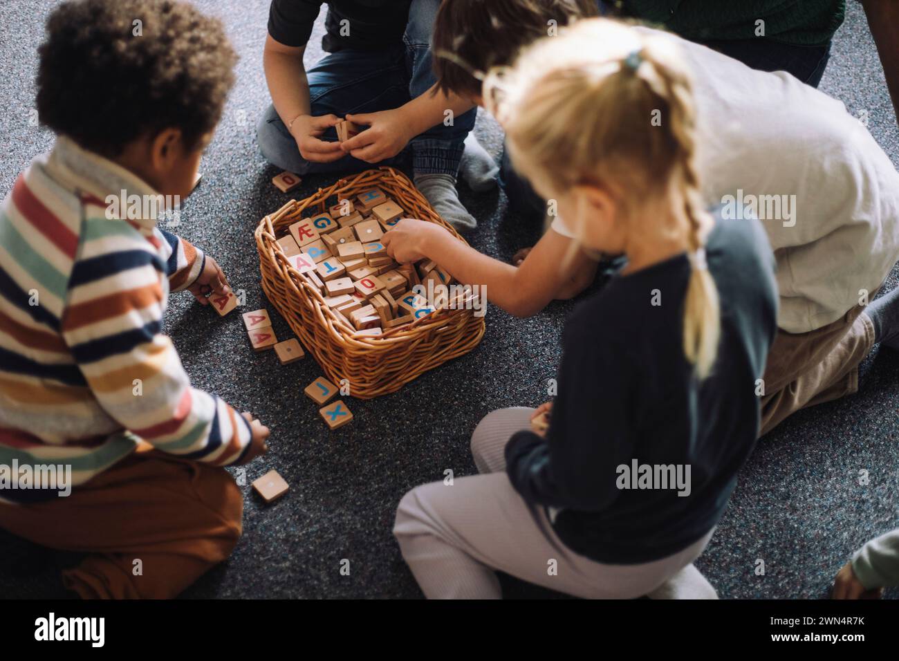High angle view of preschool kids playing puzzle game while sitting in classroom at day care center Stock Photo
