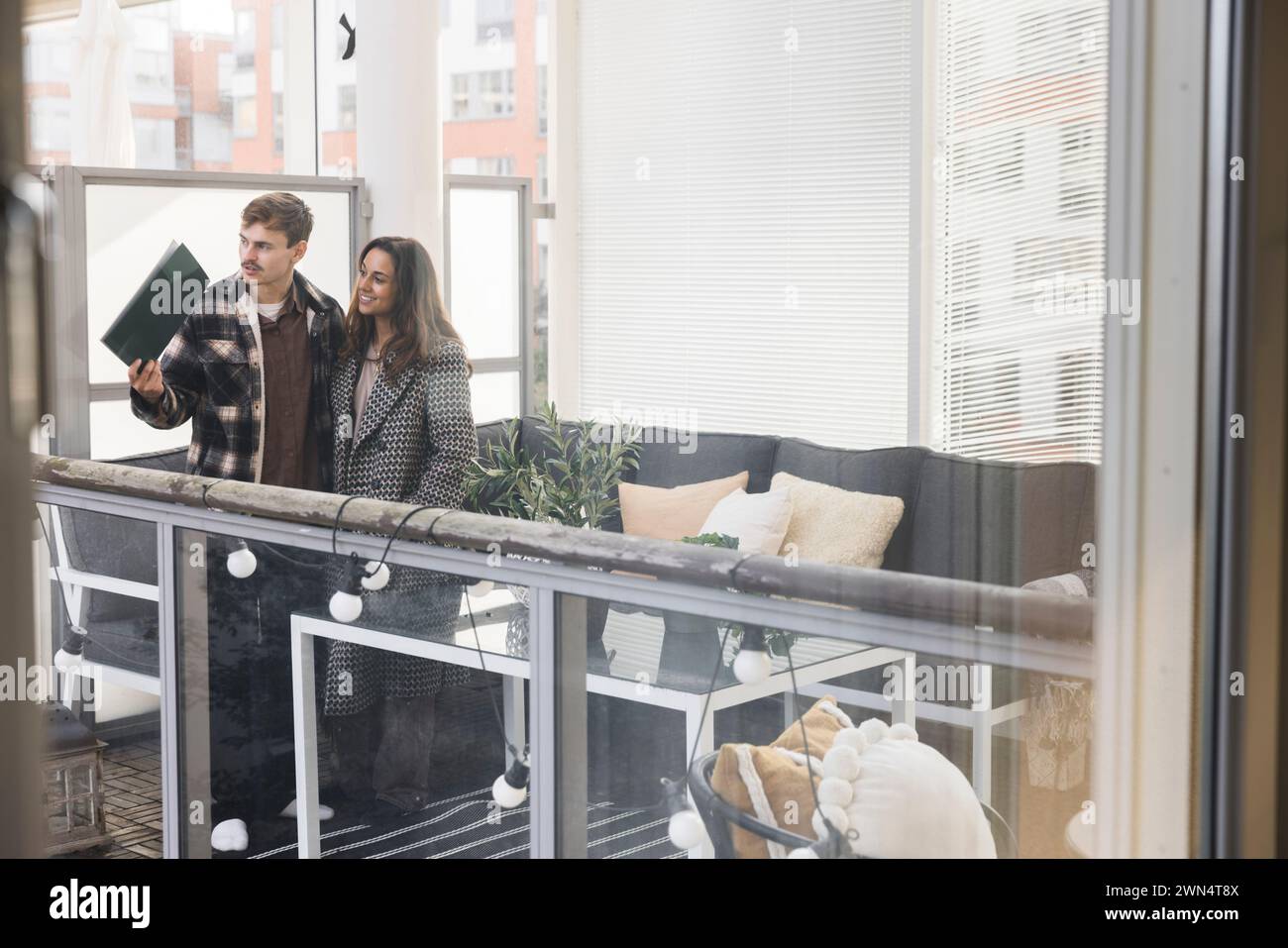 Multiracial couple looking through window while exploring new house Stock Photo